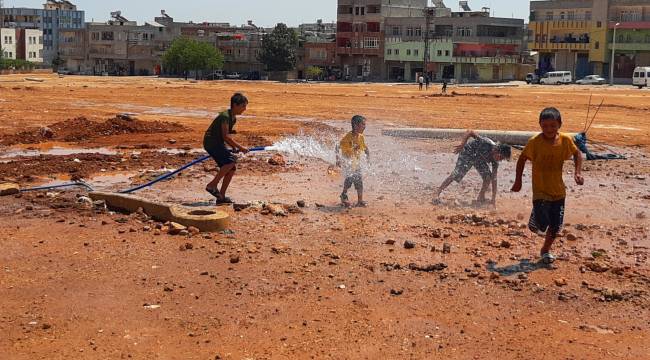 Sıcaktan bunalan çocuklar çamurda halay çekip hortumla serinledi
