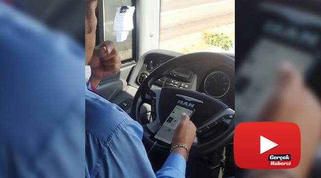 Şehirlerarası otobüs şoförünün bir elinde telefon, bir elinde çekirdek